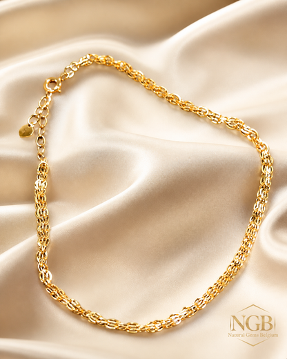 Gold chain bracelet on a beige satin background with NGB logo.